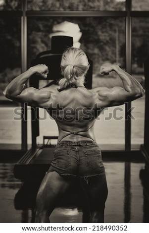 Serious Woman Bodybuilder Standing In The Gym And Flexing Muscles