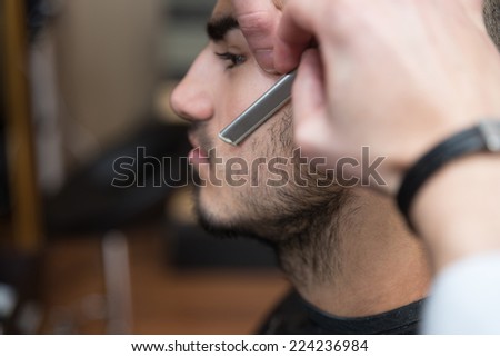 Hairdresser Shaving Man\'s Chin With A Straight Razor - Handsome Young Hairdresser Giving A New Haircut To Male Customer At Parlor
