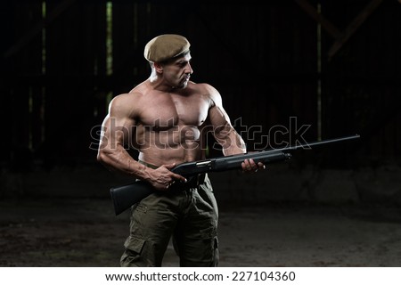 Confident Man Portrait With Machine Gun - Standing In Abandoned Building Wearing Green Pants
