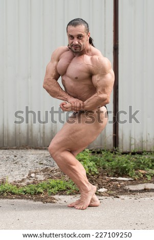 Muscular Man Flexing Muscles - Serious Bodybuilder Standing Outdoors