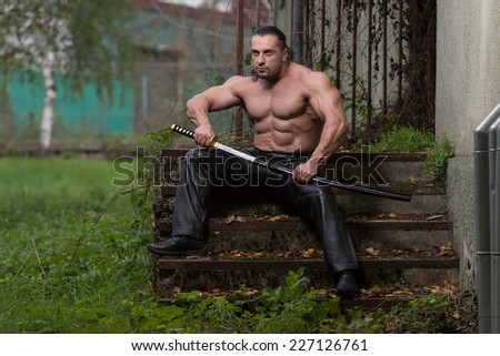 Portrait Of A Man With Ancient Sword - Standing In Forest Wearing Leather Pants