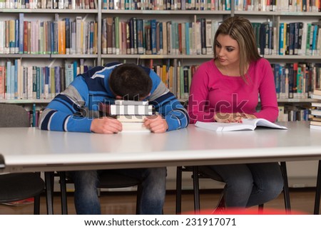 Stressed Students Of High School Sitting At The Library Desk - Shallow Depth Of Field