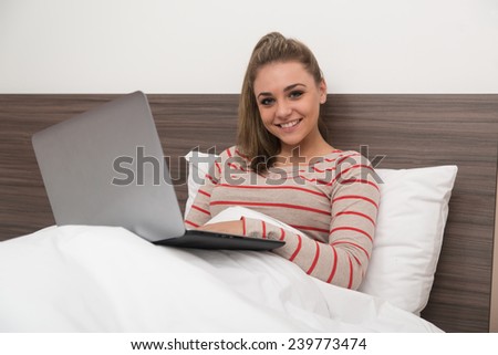 Young Woman Lying On Bed And Having Fun With Laptop In Bedroom