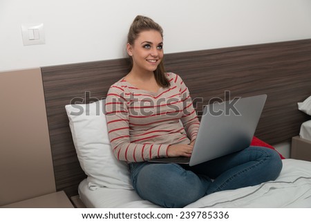 Young Female Student Lying On Bed And Having Fun With Laptop In Bedroom