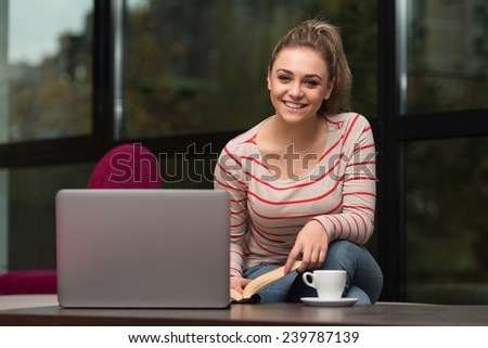 Young Female Student Drinking And Having Fun With Laptop In Cafeteria