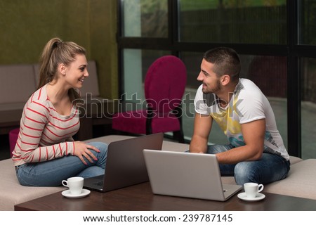Two Beautiful Students Drinking And Having Fun With Laptop In Cafeteria