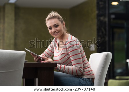 Young Woman Student Drinking And Having Fun With Tablet In Cafeteria