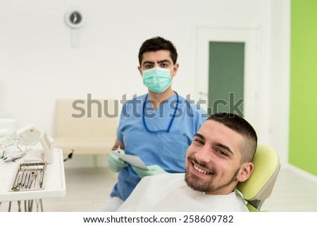 Happy Smiling Patient Says Personal Information While The Dentist Writes On The Card