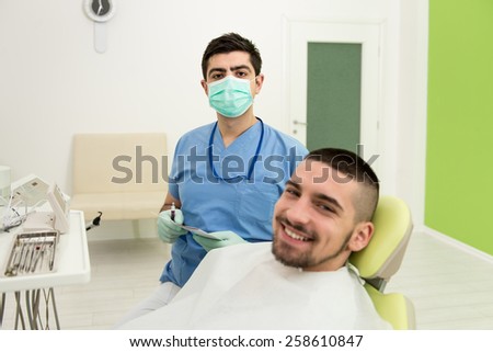 Happy Smiling Patient Says Personal Information While The Dentist Writes On The Card