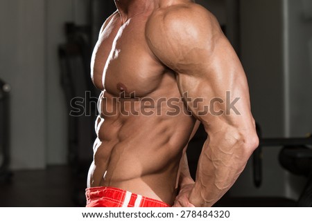Mature Man Standing In Modern Fitness Center And Flexing Muscles