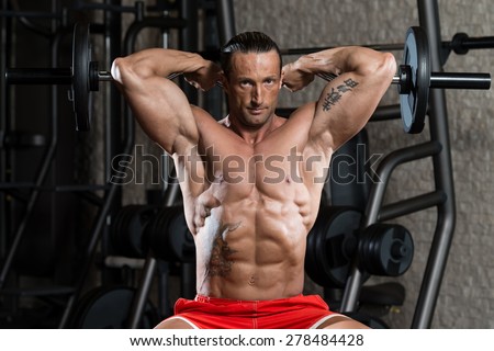 Muscular Mature Man Doing Heavy Weight Exercise For Triceps In Modern Fitness Center
