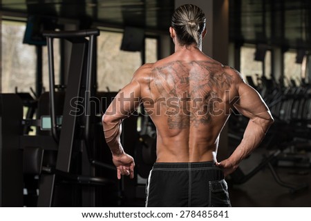 Portrait Of A Physically Fit Man In Modern Fitness Center - Showing Back Poses