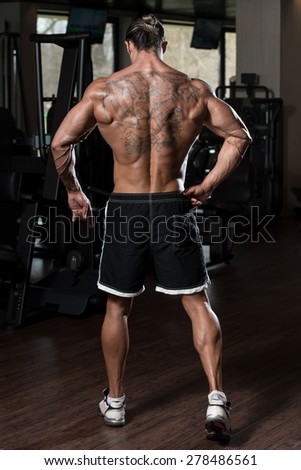 Portrait Of A Physically Fit Man In Modern Fitness Center - Showing Back Poses