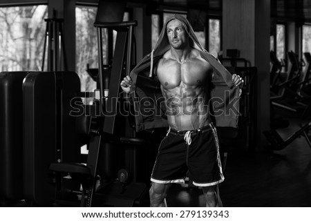 Portrait Of A Physically Fit Man In Hoodie - In Modern Fitness Center - Showing His Six Pack - Black And White Photo