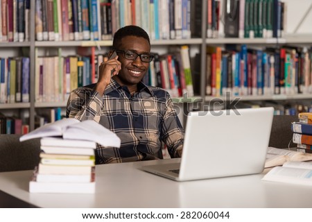 African Male Student Talking On The Phone In Library - Shallow Depth Of Field