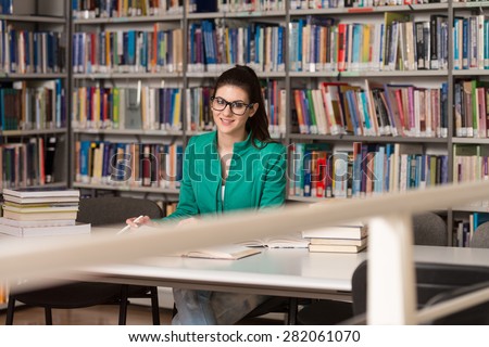 Portrait Of Clever Student With Open Book Reading It In College Library - Shallow Depth Of Field