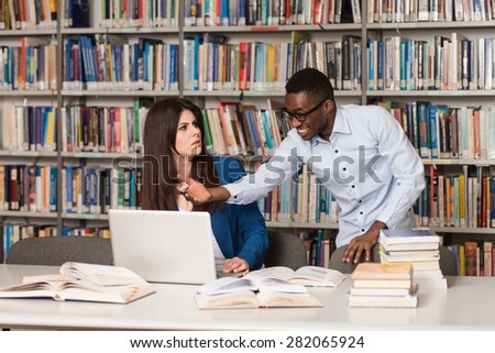 Male Student Laughing AT College  - Handsome Two College Students With Laptop And Books Working In A High School - University Library - Shallow Depth Of Field