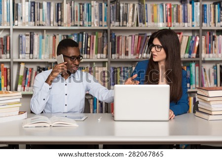 Male Student Laughing AT College  - Handsome Two College Students With Laptop And Books Working In A High School - University Library - Shallow Depth Of Field