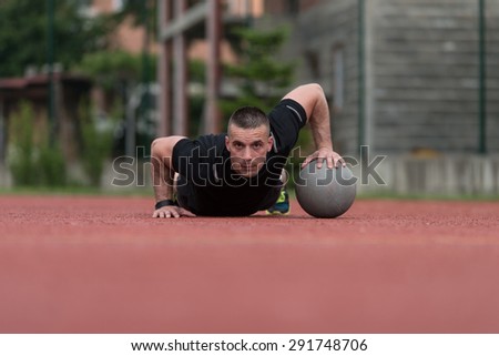 Young Man Outdoors Performing Push Ups On Medicine Ball Bodybuilding Exercise