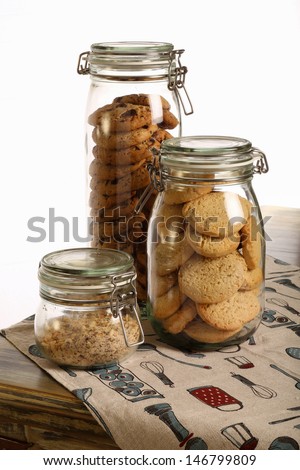 Chocolate and lavender cookies and crushed hazelnuts in a jar on rustic table with tablecloth and white background