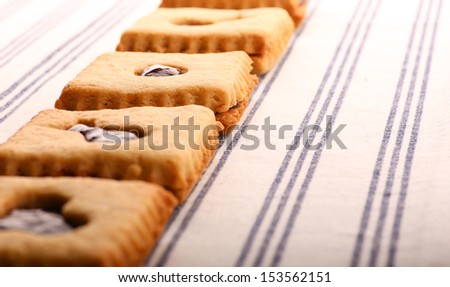 Hazelnut biscuits cookies with mixed berry jam  on striped tablecloth