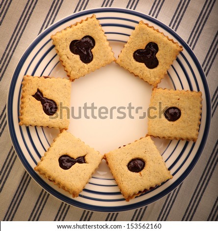 Hazelnut biscuits cookies with mixed berry jam on blue striped serving plate and striped tablecloth