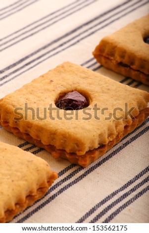 Hazelnut biscuits cookies with mixed berry jam  on striped tablecloth