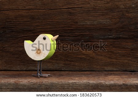 Wooden green toy bird figure symbol on old rough background with copy space