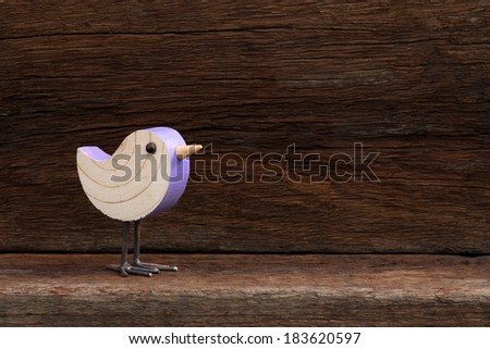 Wooden pink toy bird figure symbol on old rough background with copy space