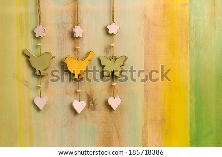 Hanging decor wooden birds, hearts and butterfly on strong over painted background