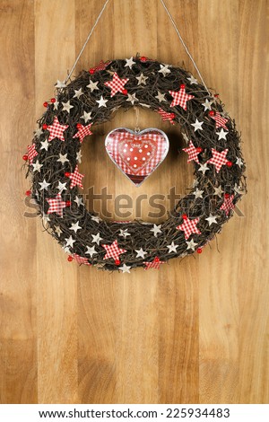 Decorated christmas door wreath with gingham birch stars and printed tin heart brown twigs on sapele wood background, copy space