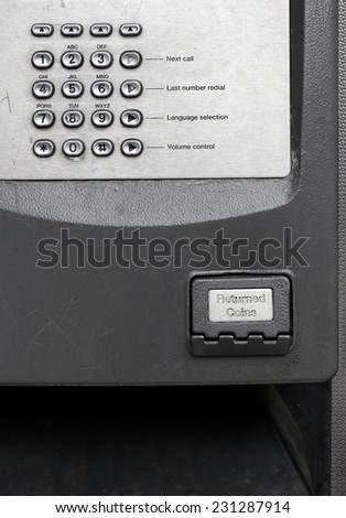 Telephone keyboard and returned coins on public phone in a telephone box