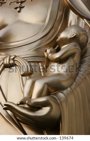 Figure of a baby in the arms of a Buddhist statue in Kyoto, Japan.
