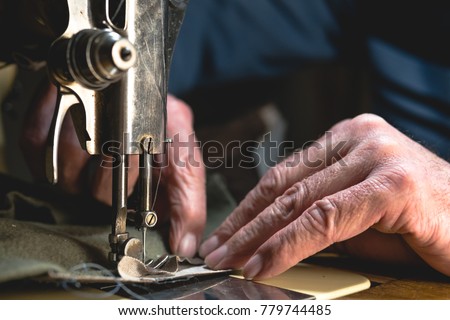 Sewing process of the leather belt. old Man\'s hands behind sewing. Leather workshop. textile vintage sewing industrial