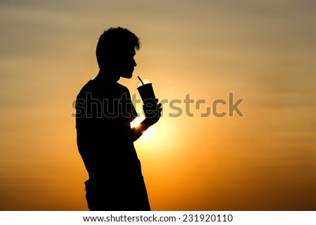 silhouette pic of a man holding a cup with straw.