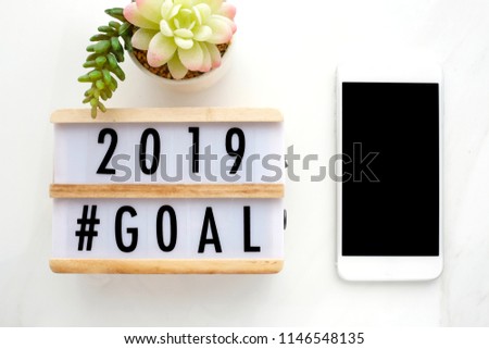 2018 goal on wood box and smart phone with blank on screen at office desk