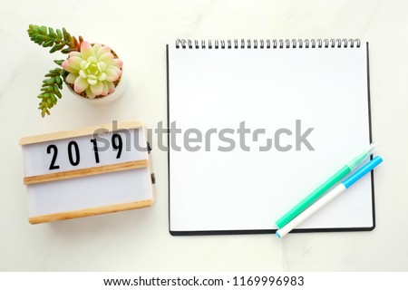 2019 on wood box, blank notebook paper on white marble table background, 2019 new year mock up, template with copy space for text, top view