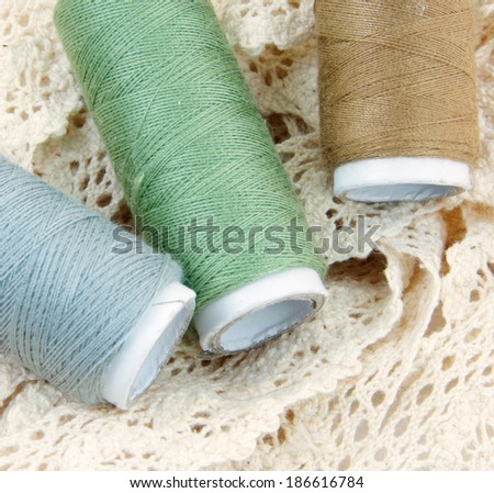 Cotton thread bobbins on cream lace.