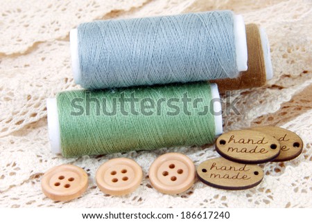 Cotton thread bobbins and wood buttons on on cream lace,sewing material.
