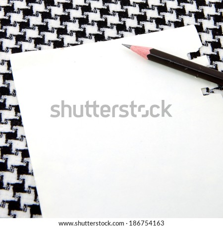 Note pad and pencil on black and white houndstooth pattern cotton.