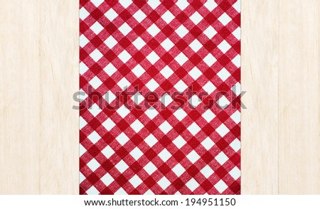 Wooden table covered with red checked tablecloth. top view.