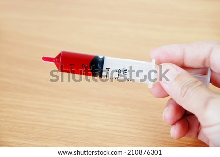 Syringe of red syrup in hand, the oral medicine.