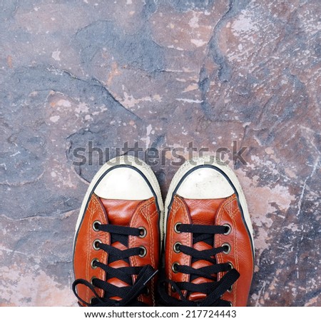 Feet in sneaker on concrete floor.