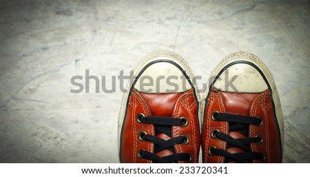 Feet in sneaker on concrete floor.
