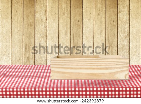 Wooden storage box on table covered with red checked tablecloth over wood wall background, for product display montage background
