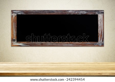 Empty vintage chalk board on table with grunge cement wall background,template,display
