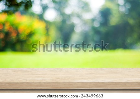 Empty wooden deck table with blur green leaves bokeh background, for product display montage