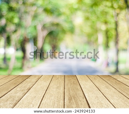 Empty perspective wood over blur park with green leaves and bokeh background, for product display montage