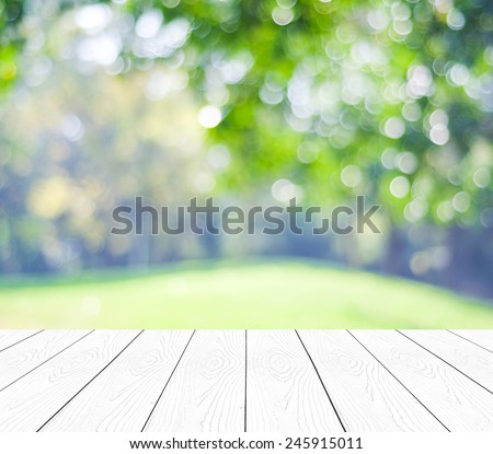 Empty perspective white wood over blurred trees with bokeh background, for product display montage