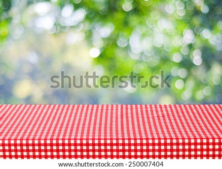 Empty table and red tablecloth over blur tree and bokeh background, for product display montage